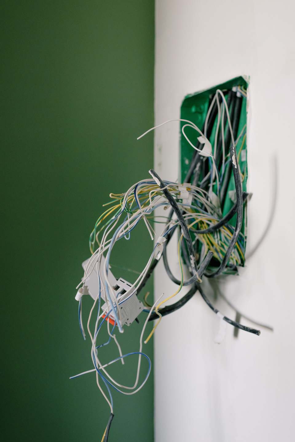 Doză electrică într-un perete, cu fire încâlcite ieșite afară, într-o locuință aflată în lucru