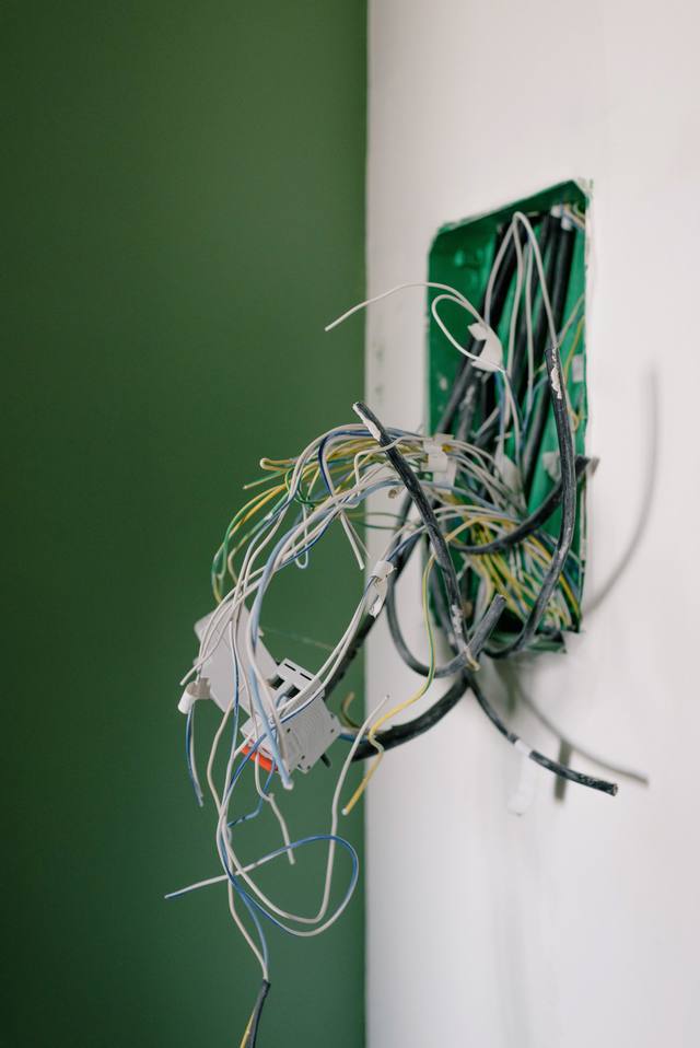 Doză electrică într-un perete, cu fire încâlcite ieșite afară, într-o locuință aflată în lucru