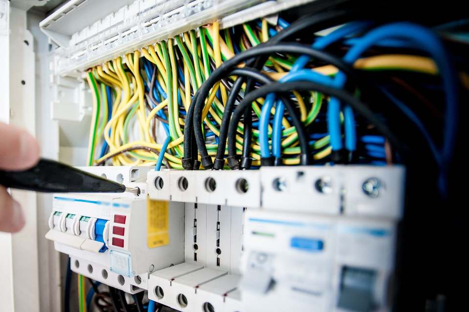 Conductori galben-verzi de împământare, legați la bara din capul unui tablou electric, cu siguranțe automate dedesubt